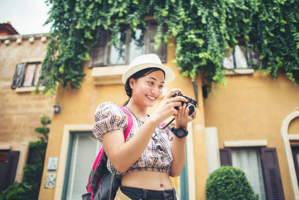 Portret van een jonge hippe vrouw die op reis is en foto 's maakt in de stad. Gelukkig en genieten met vakantie - Foto, afbeelding