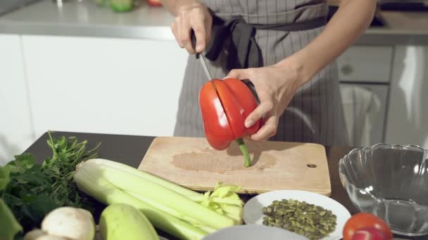 Gros plan mains de cuisinière coupant du poivre pour la salade sur une planche de bois dans la cuisine. Une alimentation saine. - Séquence, vidéo