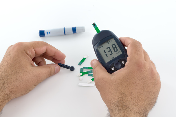 ilaç, diyabet, glisemi, sağlık ve insan konsepti - evdeki kan şekeri seviyesini glukometre ve test şeridi ile ölçen adama yakın çekim. - Fotoğraf, Görsel
