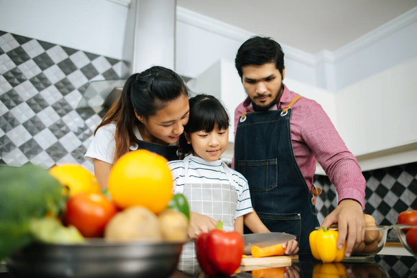 Сімейний час приготування їжі: щаслива мама вчить дочку рубати овочі, готуючи інгредієнти для приготування їжі на кухні вдома
. - Фото, зображення