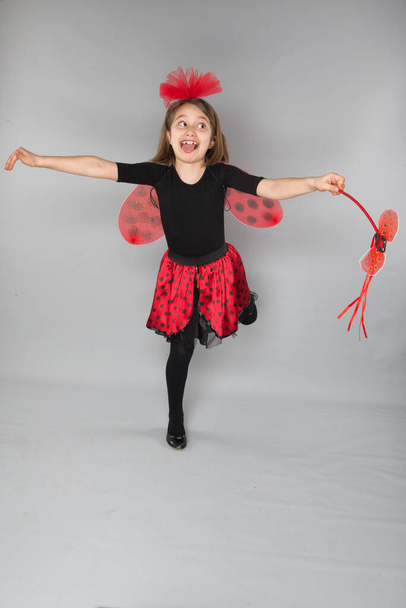 beautiful little girl wearing in carnival ladybug costume on a gray background - Photo, image