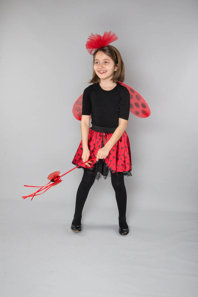 beautiful little girl wearing in carnival ladybug costume on a gray background - Zdjęcie, obraz