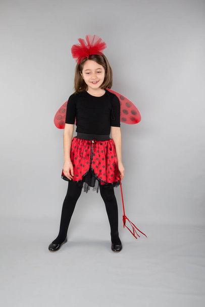 beautiful little girl wearing in carnival ladybug costume on a gray background - Foto, afbeelding