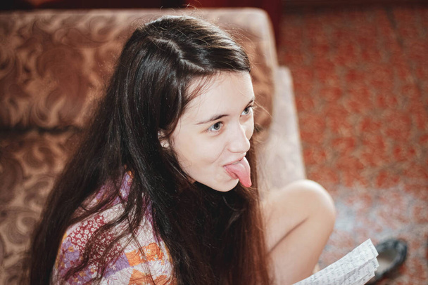 Schattig meisje laat haar tong zien aan iemand die plaagt. Bovenaanzicht, selectieve focus. - Foto, afbeelding