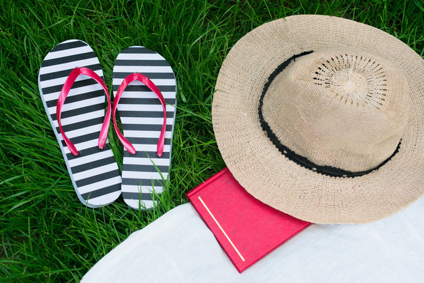 Libro de sombreros de sol chanclas sobre hierba verde. Concepto vacaciones de verano
. - Foto, Imagen