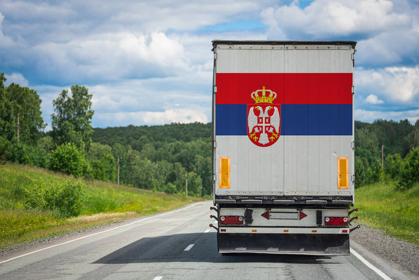 バックドアに描かれたセルビアの国旗を持つトラックは、高速道路沿いの他の国に商品を運びます。輸出入、輸送、商品の国内配送の概念  - 写真・画像