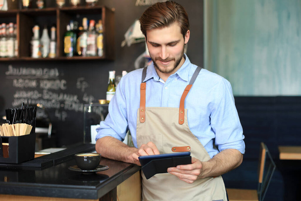 Young male owner using digital tablet while standing in cafe - Photo, Image