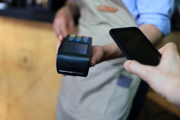 Cliente que utiliza el teléfono inteligente para el pago al propietario en el restaurante cafetería, tecnología sin efectivo - Foto, Imagen