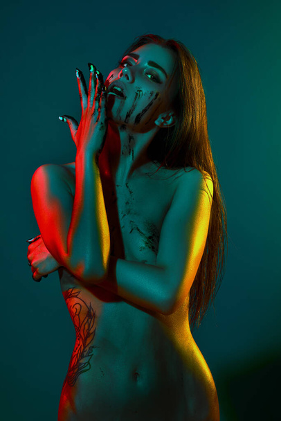 fashion art photo of elegant nude model with black paint in the light colored spotlights - Valokuva, kuva
