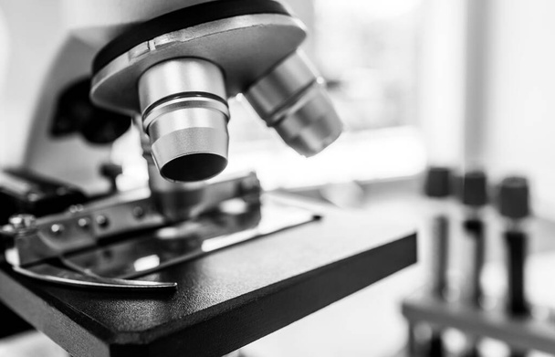 Nahaufnahme von Mikroskop und Blutteströhrchen im Labor für Experimente über neue Impfstoffe und Medikamente. Wissenschaftskonzept - Foto, Bild