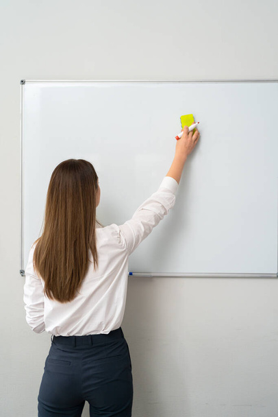Junge Frau schreibt im Büro auf Whiteboard, - Foto, Bild