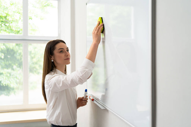 Young woman writing on a whiteboard in an office, - Photo, Image