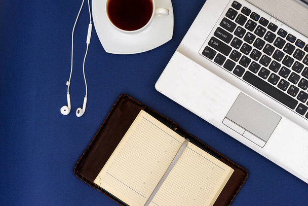 Moderner Arbeitsplatz, Laptop und Zubehör auf blauem Hintergrund - Foto, Bild