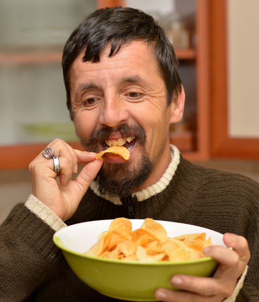 Portrait de jeune homme brune mangeant des chips
 - Photo, image