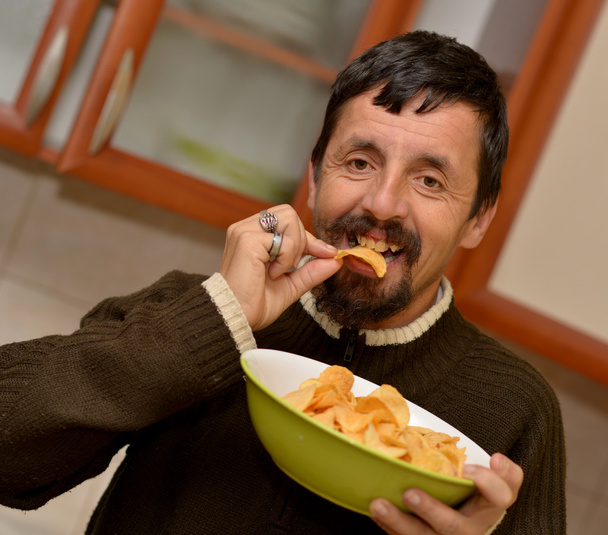 Portrait of young brunette man eating chips - Photo, Image