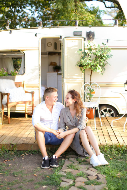 若いヨーロッパのカップルは、車輪の上に家の近くに座っていると抱擁. - 写真・画像