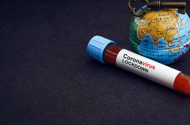 CORONAVIRUS LOCKDOWN texto con globo terráqueo, llave y tubo de vacío de análisis de sangre sobre fondo negro. Concepto de Covid-19 o Coronavirus
  - Foto, Imagen