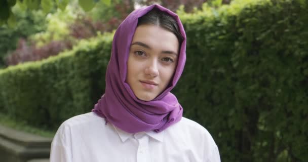 Schöne junge Frau, die in die Kamera schaut und ein traditionelles Kopftuch trägt. Attraktive Frau im Hidschab - Filmmaterial, Video