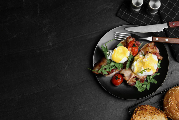 Delicious eggs Benedict served on black table, flat lay. Space for text - Φωτογραφία, εικόνα