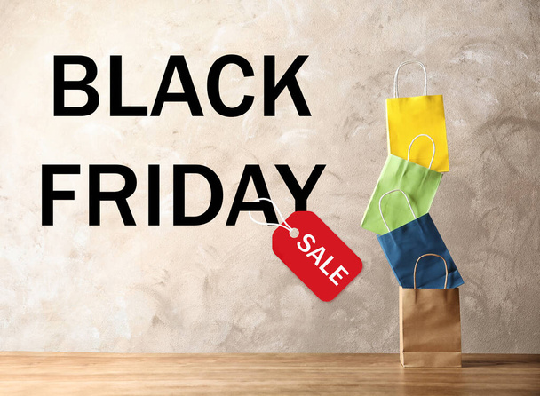 Colorful shopping bags and text BLACK FRIDAY SALE on beige background - Foto, afbeelding