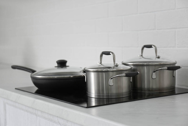 Saucepots and frying pan on induction stove in kitchen - Foto, afbeelding