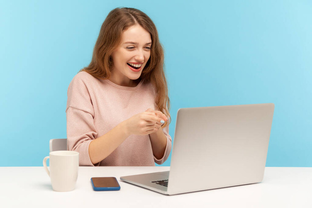 Hey, we need you! Positive businesswoman in casual clothes pointing to laptop screen, choosing lucky winner while talking on video call, sitting at workplace home office. indoor studio shot, isolated - Foto, immagini