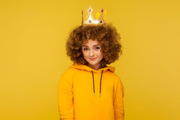 I am queen! Lovely happy curly-haired hipster woman wearing crown on head and smiling, concept of self confidence in success, self-motivation and dreams to be best. indoor studio shot, isolated - Photo, image