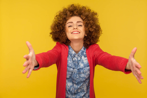 Who wants free hugs? Portrait of friendly curly-haired woman welcoming with wide raised hands and ready to embrace, sharing love, sincere meeting guests with smile. indoor studio shot, isolated - Fotografie, Obrázek