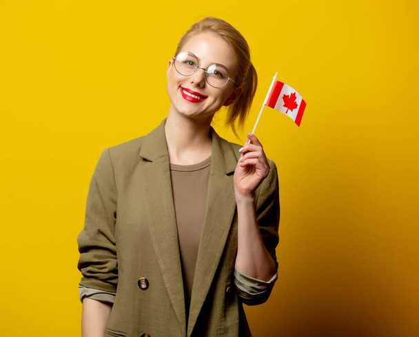 Style femme blonde en veste avec drapeau canadien sur fond jaune - Photo, image