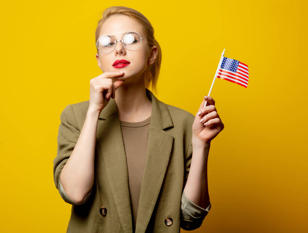 Style blonde woman in jacket with flag of USA on yellow background - Фото, изображение