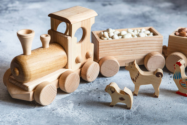 Παιδικά ξύλινα παιχνίδια. Παιδικό ξύλινο τρένο με βαγόνια. Φυσικό ξύλινο σετ κατασκευής. Εκπαιδευτικός εξοπλισμός. Παιδική ξύλινη ατμομηχανή με διάφορα φορτία σε άμαξες. - Φωτογραφία, εικόνα