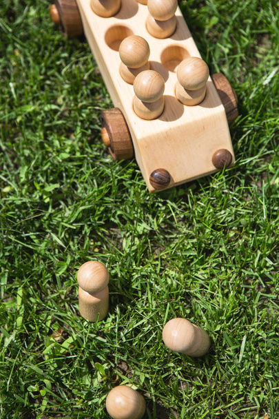 Juguetes de madera para niños. Niños coche de madera con pasajeros en el césped de hierba verde. Conjunto de construcción de madera natural. Equipos educativos
.  - Foto, imagen