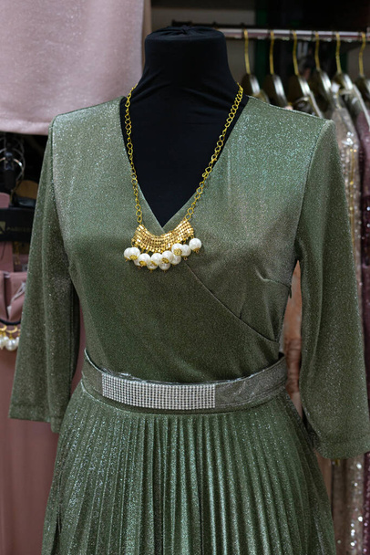 Zelené šaty s opaskem zavěšeným na figuríně. Maloobchod - Fotografie, Obrázek
