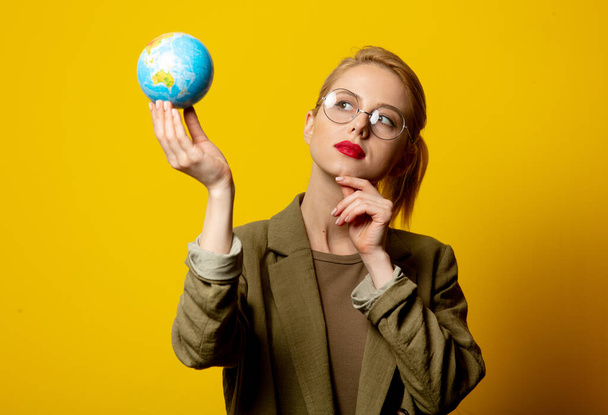 Tyyli blondi nainen takki pidä Globe keltaisella taustalla - Valokuva, kuva