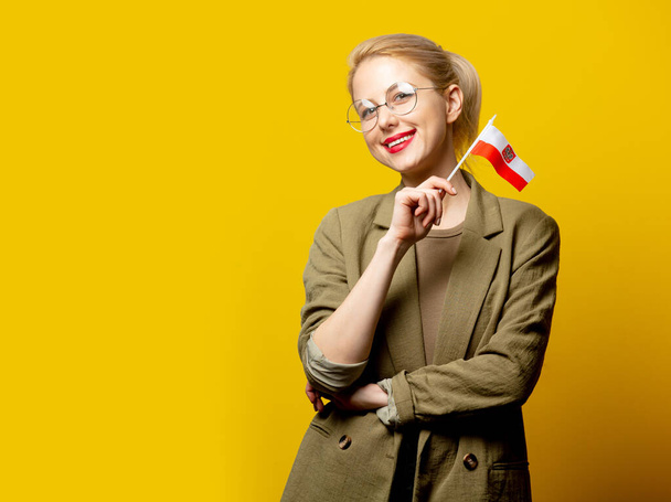Style blonde woman in jacket with Polish flag on yellow background - Foto, Imagen