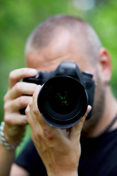 Portrait d'un photographe masculin couvrant son visage avec l'appareil photo en plein air photo, Journée mondiale du photographe, Jeune homme avec un appareil photo à la main. - Photo, image