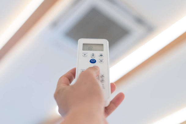 Focus op Power knop van Air Conditioner Afstandsbediening, te openen en uit te schakelen bij plafonds van seminarzaal. - Foto, afbeelding