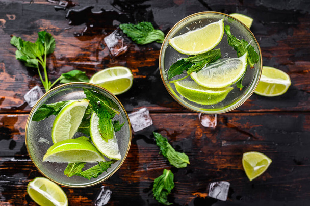 Fresh drink lemonade mojito. Mojitos with mint leaves, lime and ice. Black wooden background. Top view. - Fotó, kép
