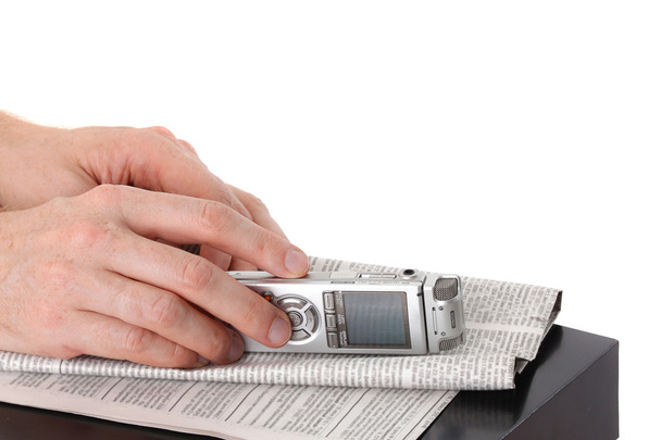 diktafon v mužské ruce a novin na černém stole izolovaných na w - Fotografie, Obrázek