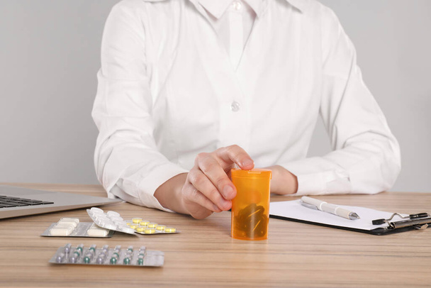 Professional pharmacist working at table against light grey background, closeup - Φωτογραφία, εικόνα