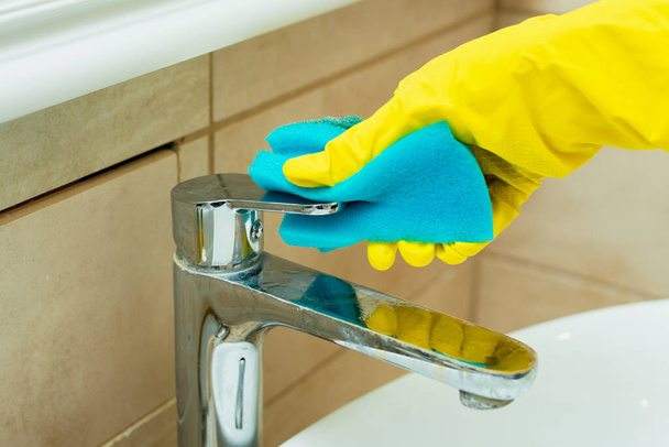 Valaki szivaccsal mossa a mosogatót. Valaki mosogatót mos sárga kesztyűben. - Fotó, kép