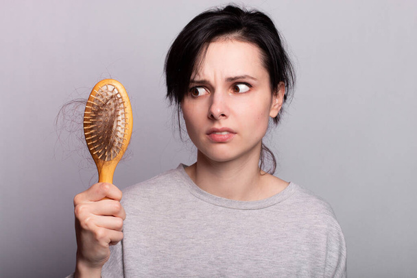 Beautiful woman comb hair grey shirt fall out - Foto, Imagen