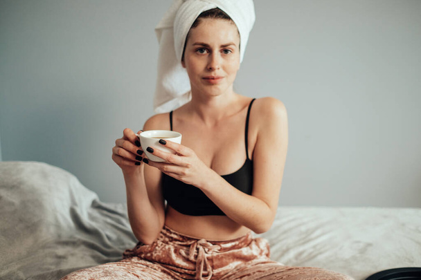 Portrait of Beautiful Young Caucasian White Adult Girl in Bath Towel Sitting on Bed - Photo, Image
