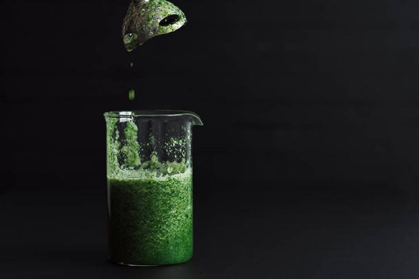 Jeden zielony koktajl smoothie stoi na czarnym stole - Zdjęcie, obraz