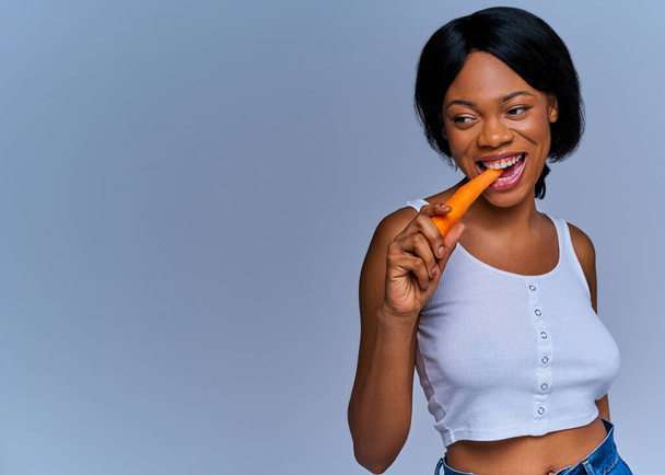 Smiling lady on diet eating fresh carrot vegetable/fruit - Foto, imagen