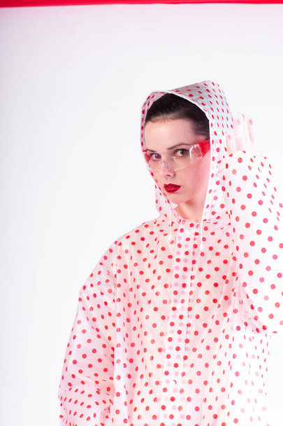 fashionable woman in a coat with red polka dots, transparent glasses, a light background - Фото, зображення