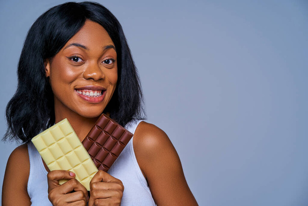 Happy slim girl with short hair with wide smile shows dark milk chocolate - Photo, Image