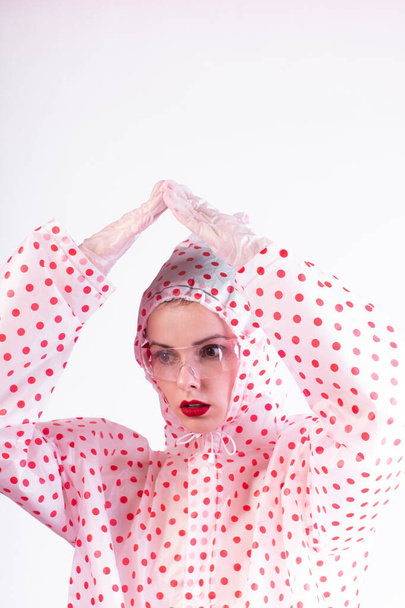 strange fashionable woman in a coat with red polka dots, transparent glasses, a light background - 写真・画像