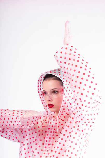 strange fashionable woman in a coat with red polka dots, transparent glasses, a light background - Fotografie, Obrázek