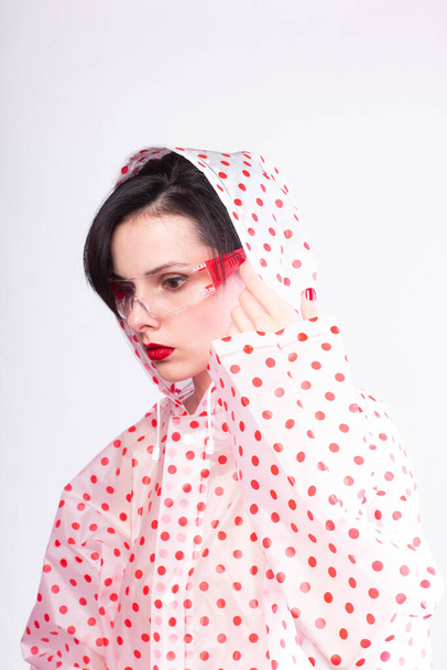 woman in a raincoat with red polka dots, transparent safety glasses, red lips - Fotografie, Obrázek